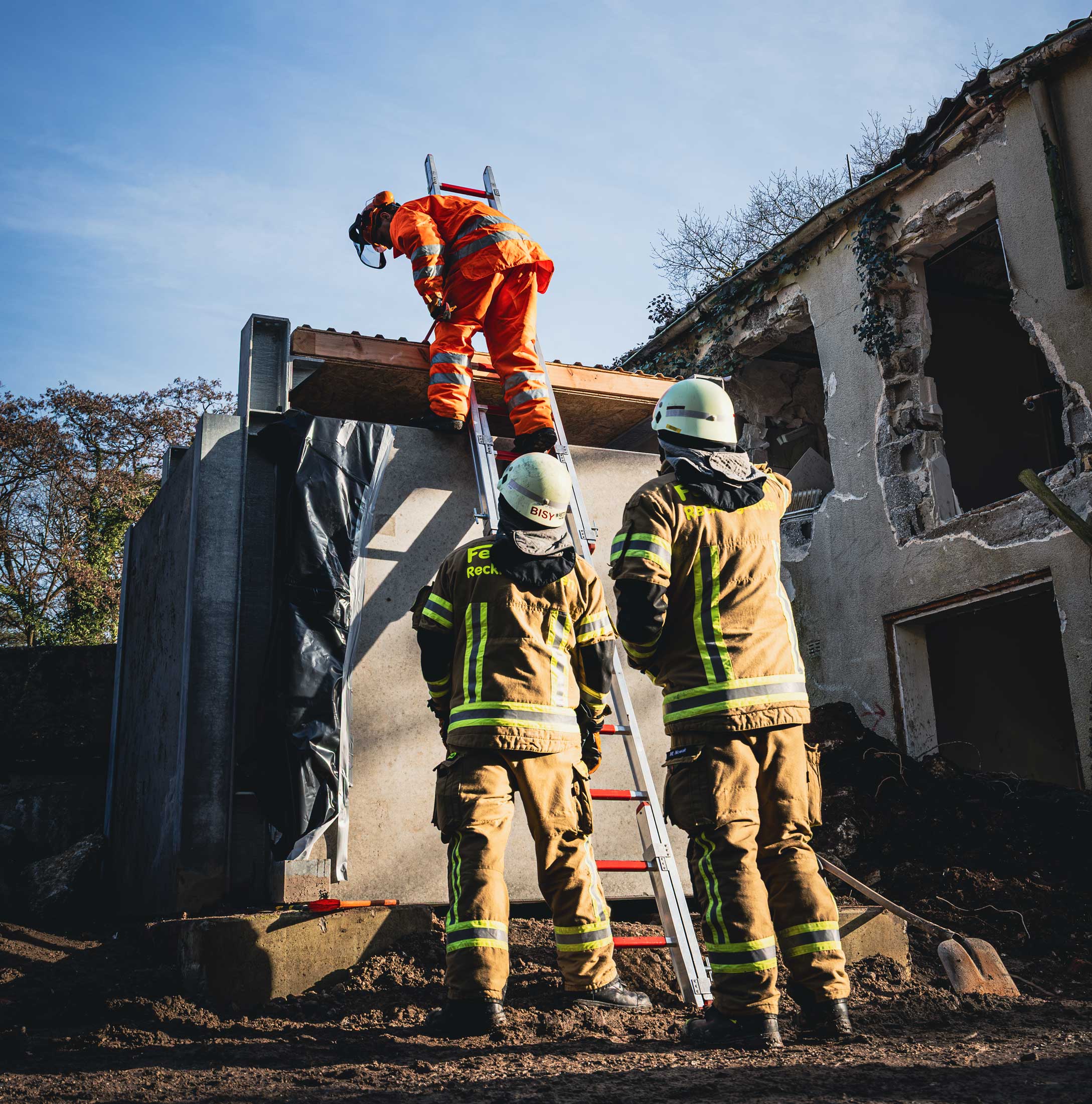 Feuerwehrmänner mit Leiter steigen von oben ins Gebäude.