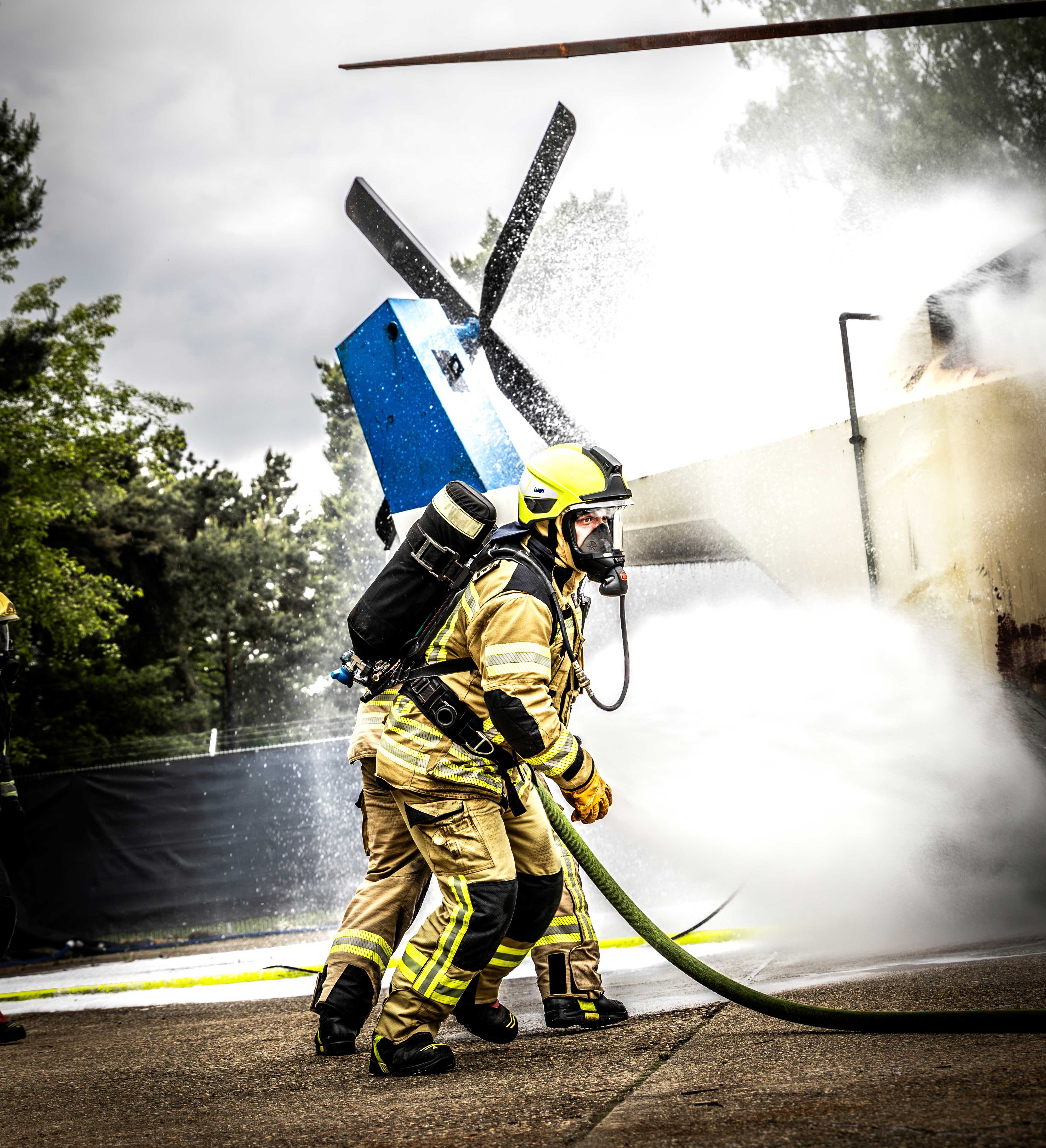 Feuerwehrmänner rennen zu einem Helikopter und löschen diesen.